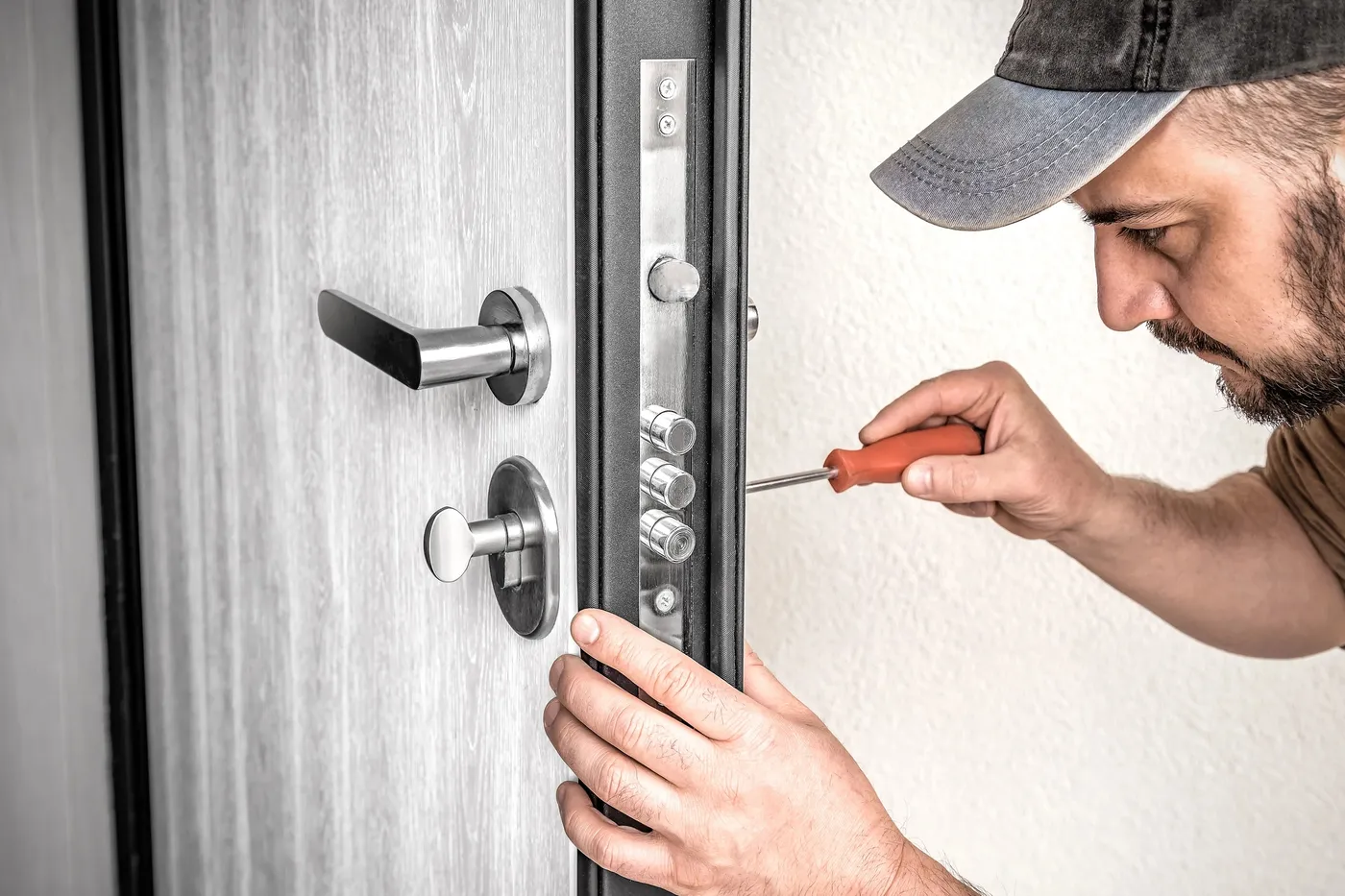 Technicien réglant le mécanisme d'une serrure de porte de hall lors d'une intervention en copropriété en Île-de-France